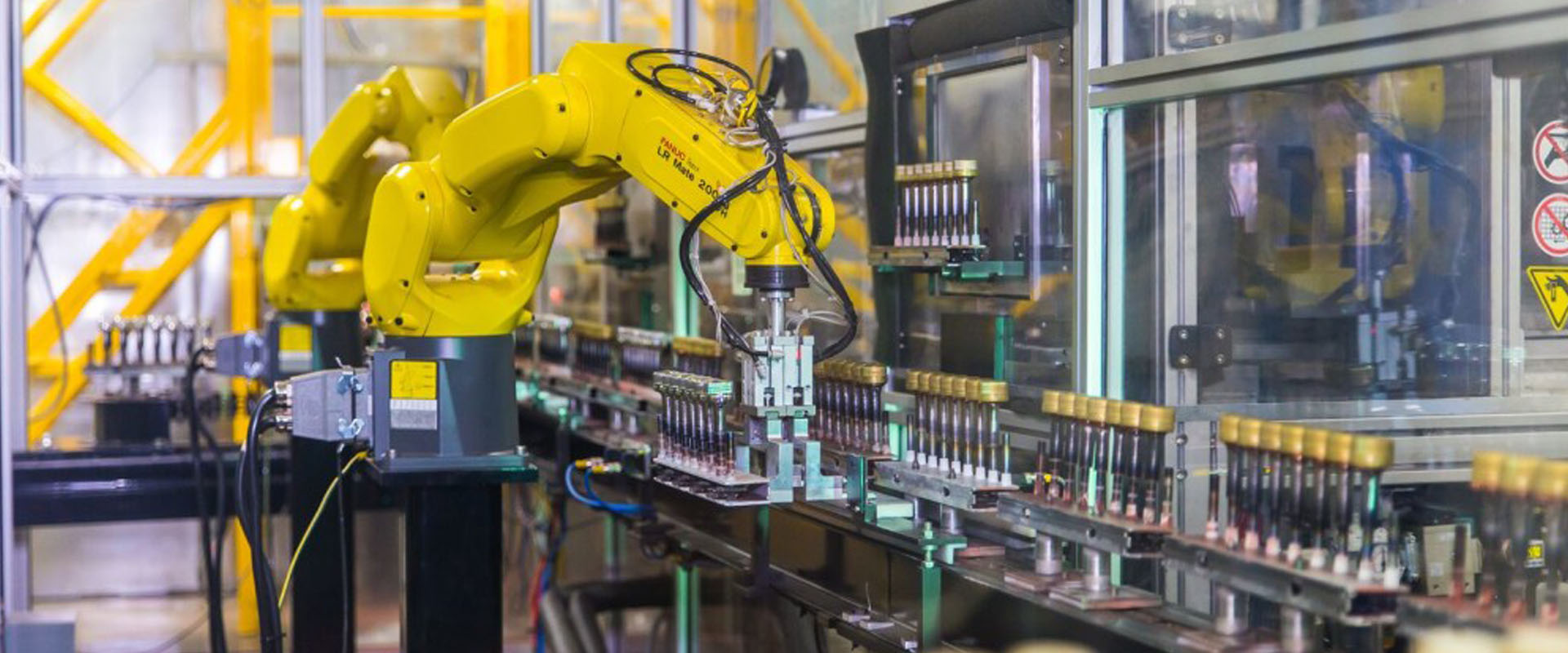 Robotic arm moving bottle caps on an assembly line at Spartek, Inc. in Sparta, Wisconsin, showcasing painting and hard coating processes.