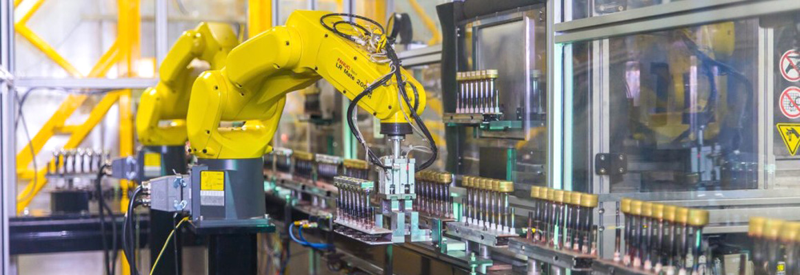 Fully automated, neon yellow, robot arm handling bottle caps at Spartek, Inc. in Sparta, Wisconsin, showcasing painting and hard coating processes.