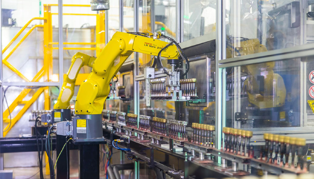 Robotic arm moving bottle caps on an assembly line at Spartek, Inc. in Sparta, Wisconsin, showcasing painting and hard coating processes.