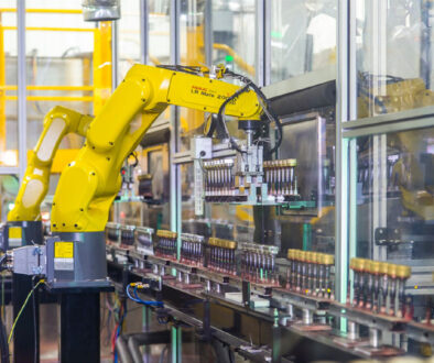 Robotic arm moving bottle caps on an assembly line at Spartek, Inc. in Sparta, Wisconsin, showcasing painting and hard coating processes.