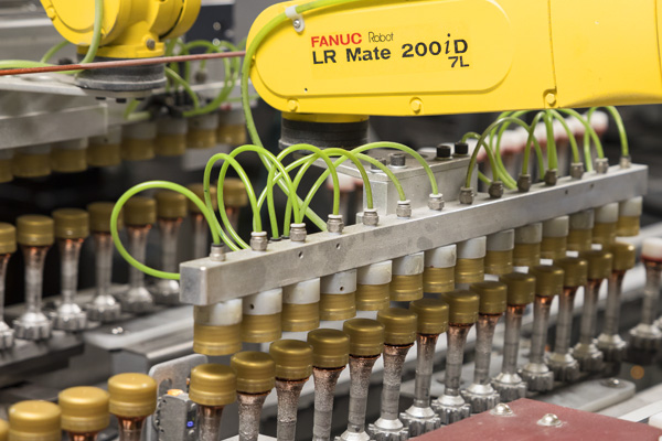 Close-up of FANUC robots in an inline vacuum metallizing production line for bottle caps at Spartek.